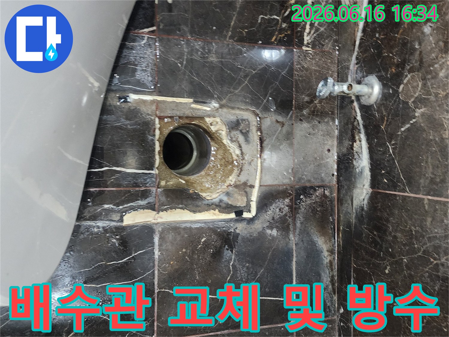 이 이미지는 욕실 배수관 주변의 낡은 타일과 시멘트를 제거하고-새로운 배관과 방수층을 설치하기 위한 준비를 보여줍니다.
