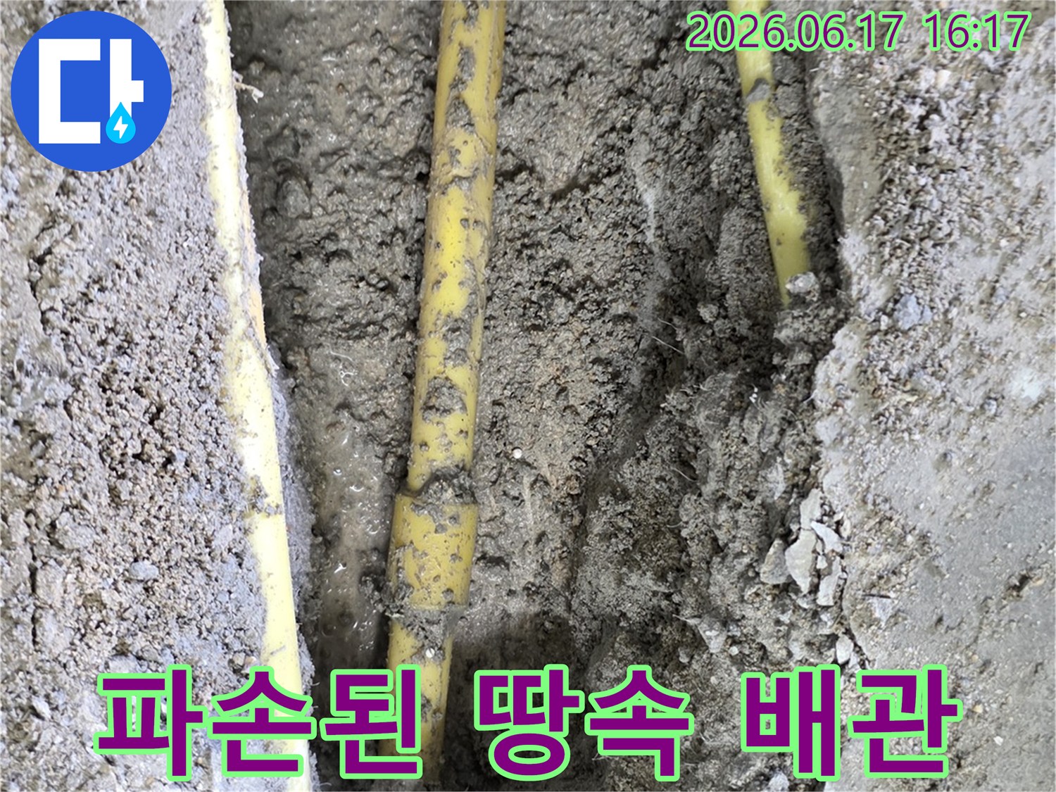 땅을 파헤쳐 드러난 노란색 배관의 파손 지점에서 누수가 발생하고 있는 모습입니다.