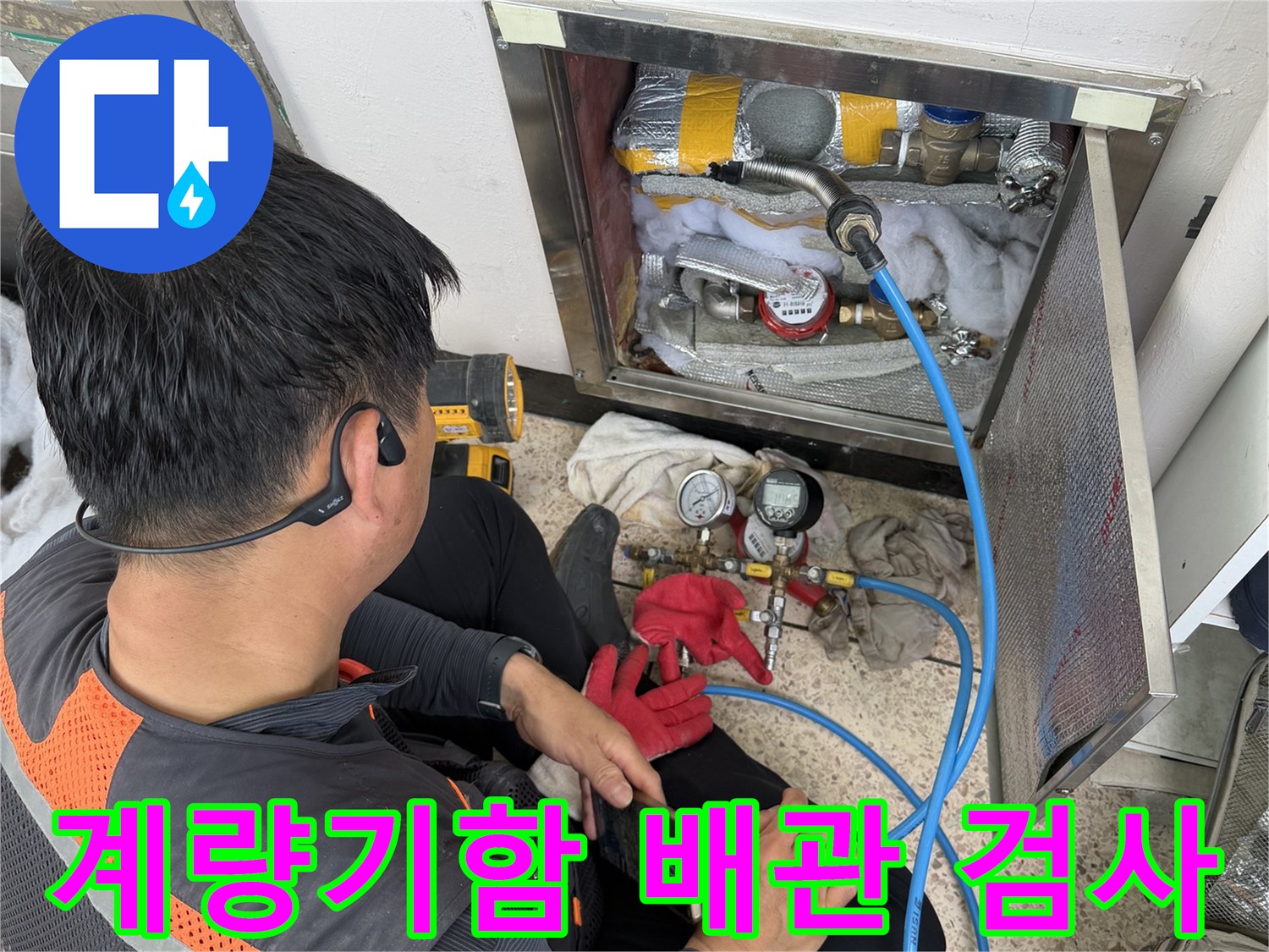 파란색 호스가 연결된 수도 계량기와 점검 중인 엔지니어의 모습