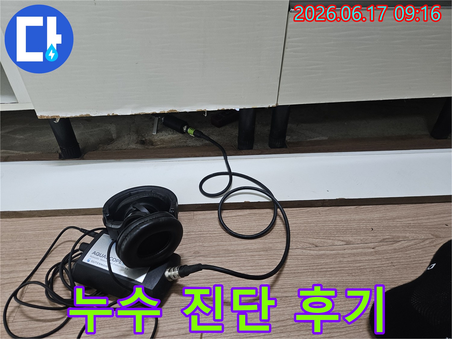 누수 탐지 엔지니어가-청음식 장비를 사용하여-싱크대 하부장 아래 누수 지점을 진단하는 모습