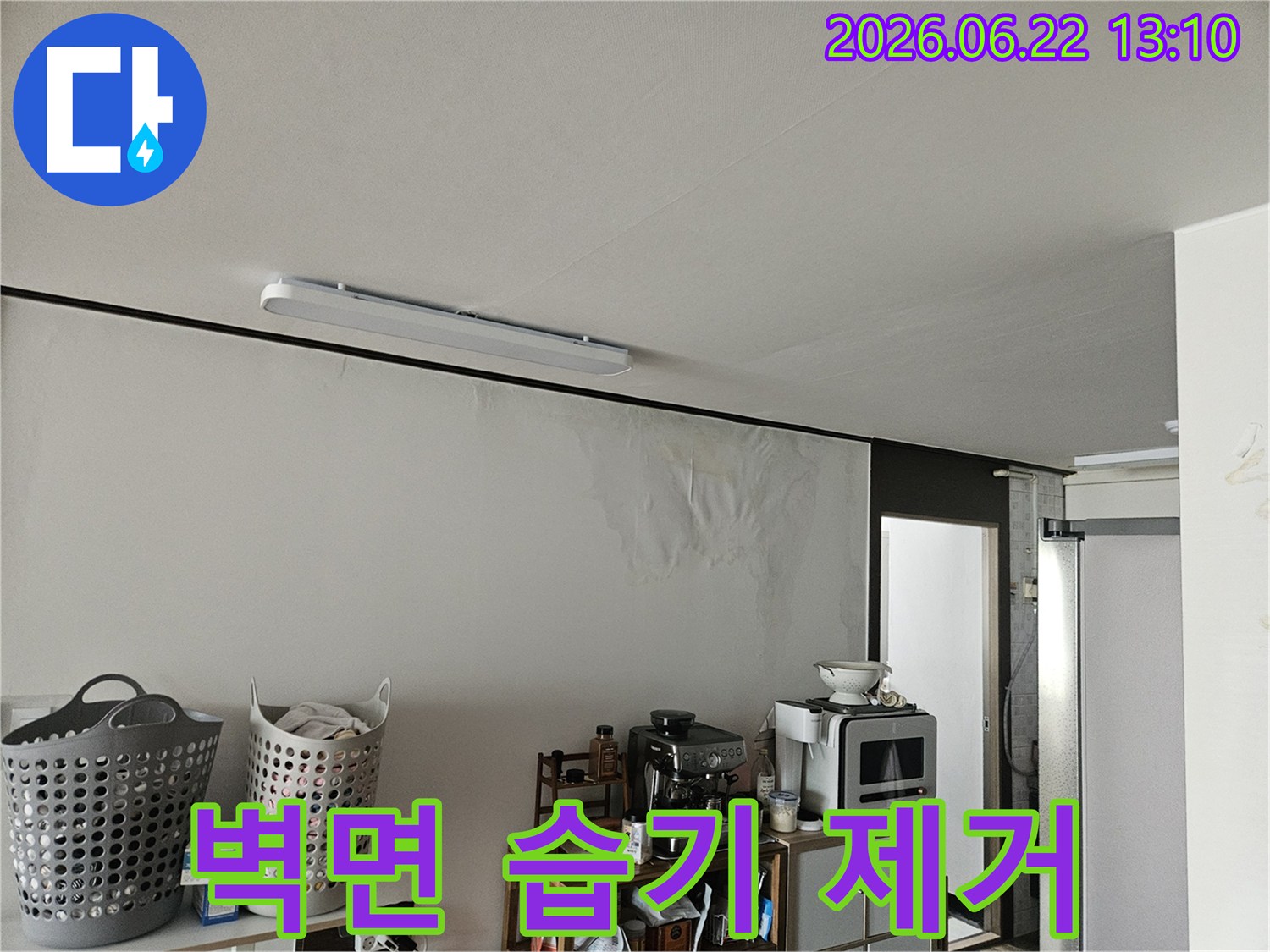 이 이미지는 천장 누수로 인해 벽면이 심하게 젖어-벽지가 들뜨고 곰팡이가 생기기 시작한 아파트 내부의 모습을 보여줍니다.