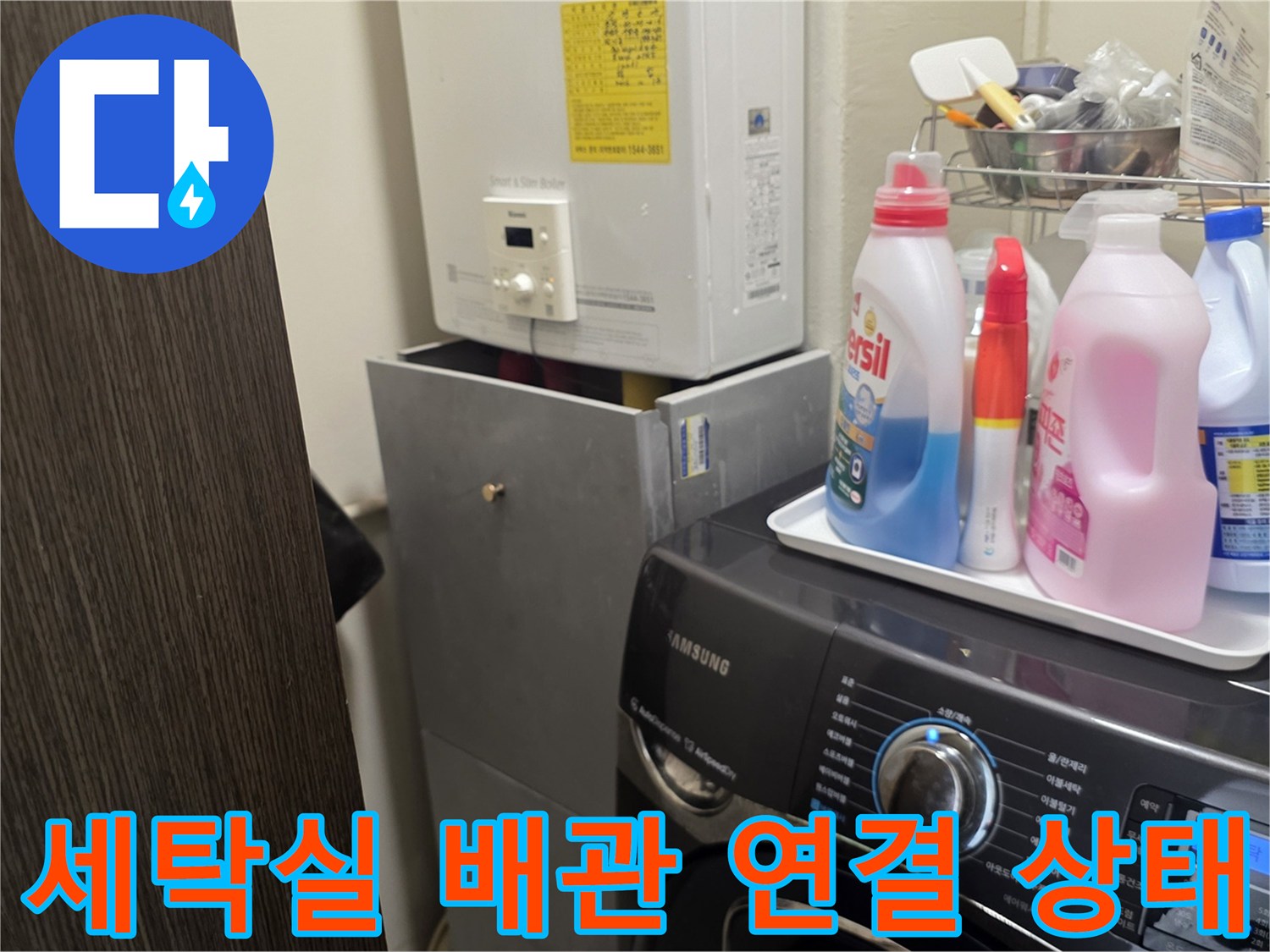 세탁기 옆 보일러 배관과 세제류가 놓인 세탁실 전경입니다.