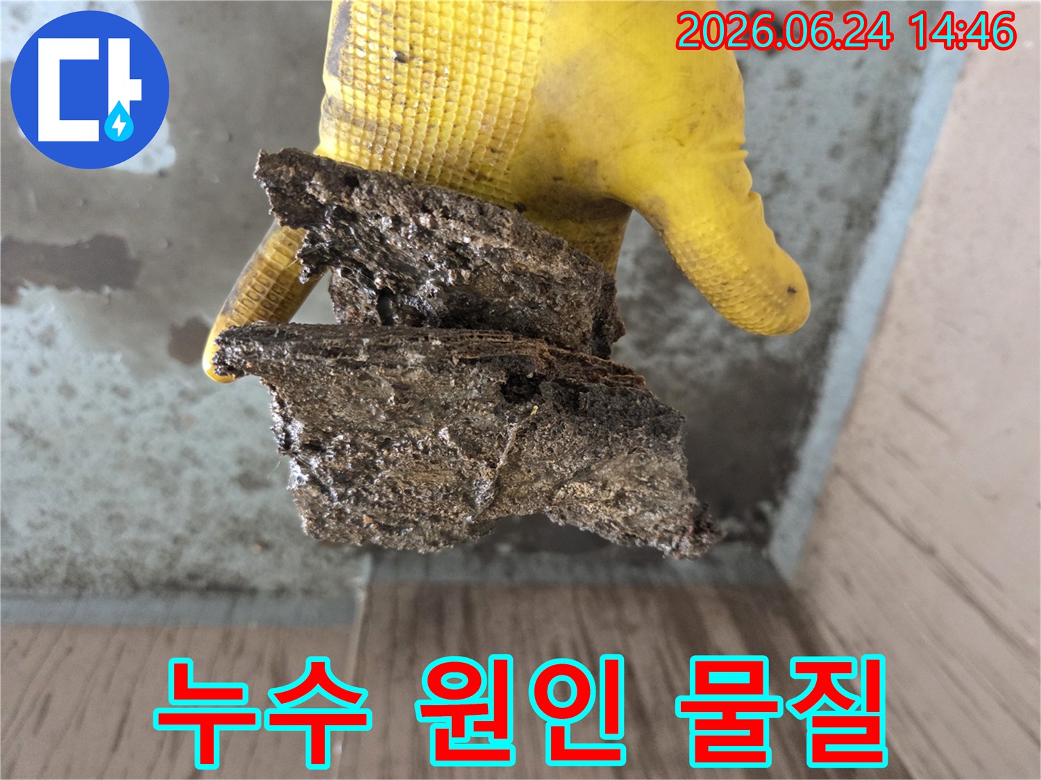 물샘-현장의-원인을-찾던-중-발견된-노후된-배관의-부식된-파편을-노란-장갑을-낀-손으로-들고-있는-사진입니다.