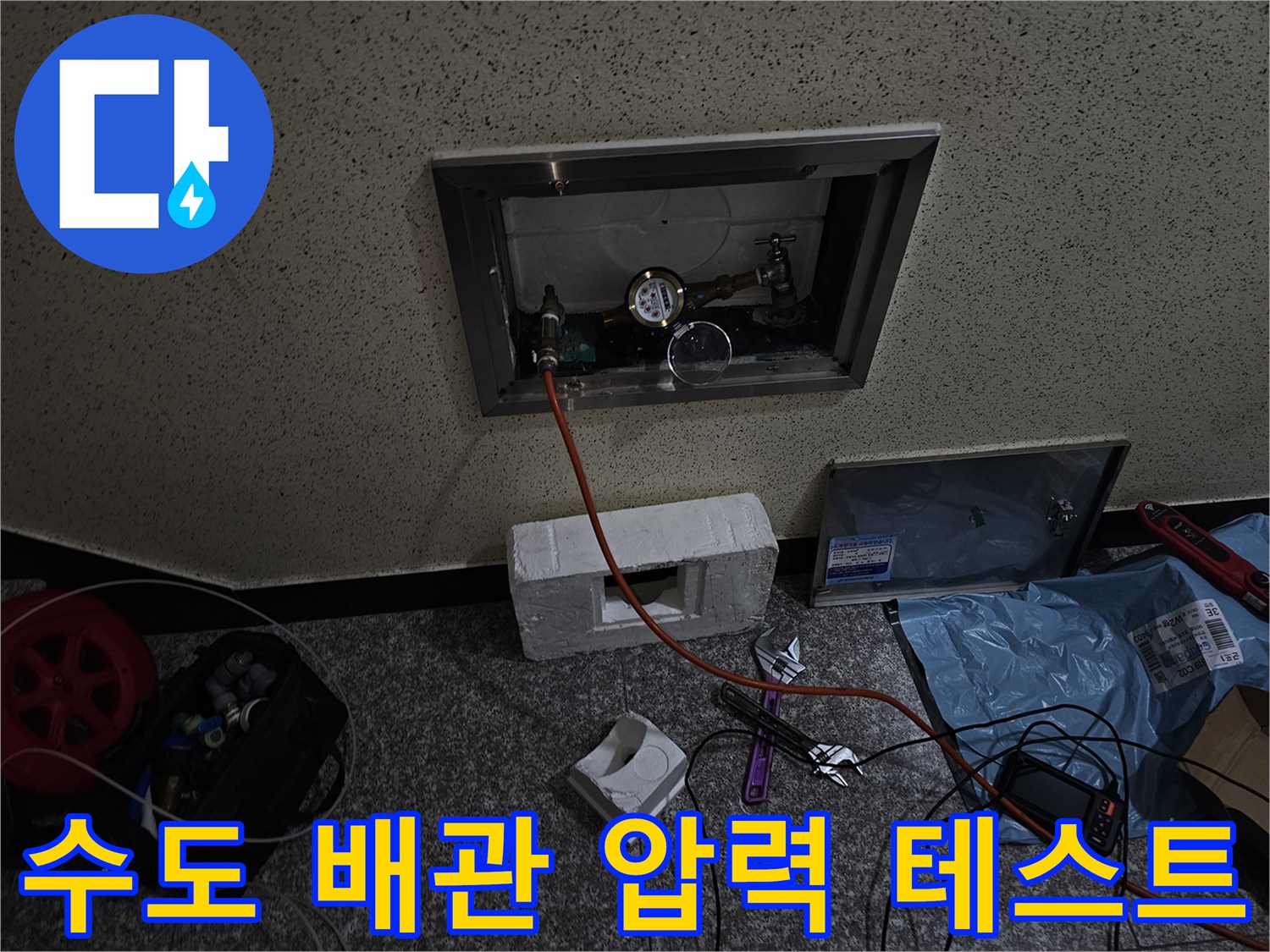 벽면 점검구 내부의 배관과 압력 측정 장비가 연결된 모습입니다.