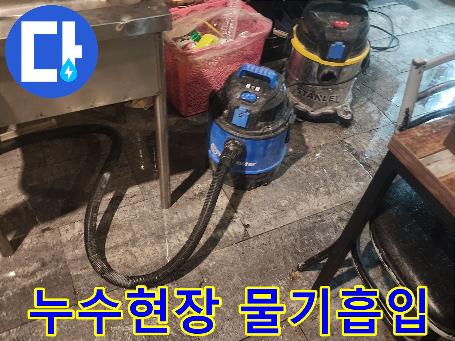 누수 현장에서-바닥의 물기를-빠르게 흡입하고-제거하기 위해-사용되는-산업용 습식 청소기 두 대가-작동 준비 중인 모습입니다.