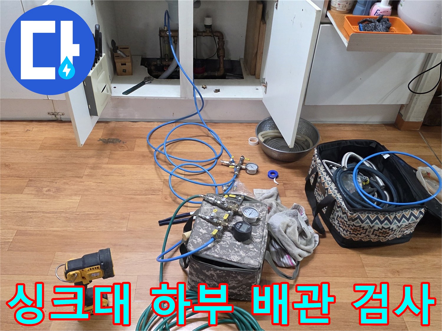 싱크대 밑 배관에 연결된 파란색 호스와 바닥의 측정 장비들