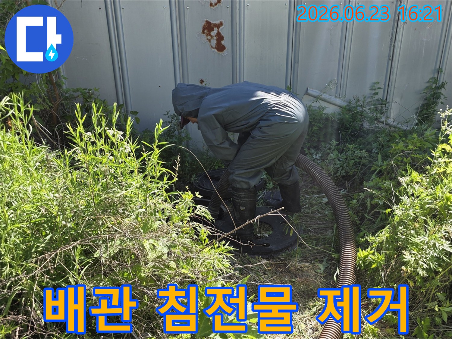 전문 작업자가 야외 배관 내부의 침전물을 제거하고 청소하기 위해 흡입 장비를 사용하는 현장