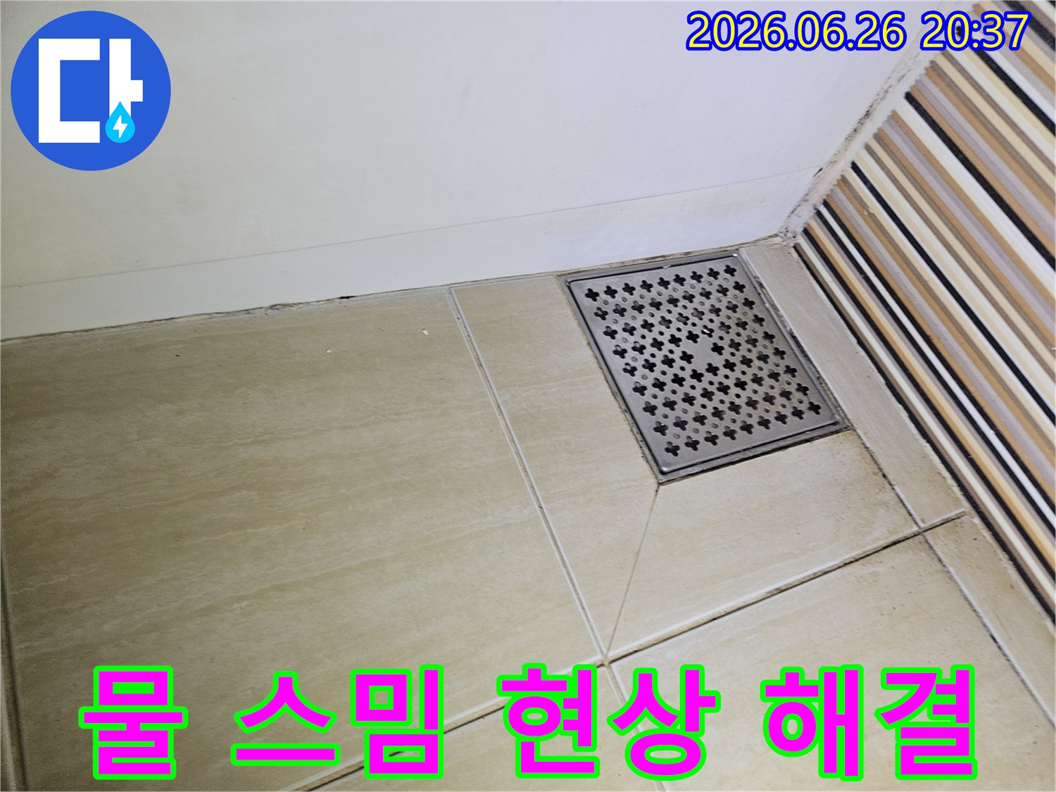욕실 바닥 타일의-줄눈과 벽면 경계에-나타난 어두운 오염은-지속적인 물 스밈으로-인한 누수 발생을-강력히 시사하며-해결이 필요함을 보여줍니다