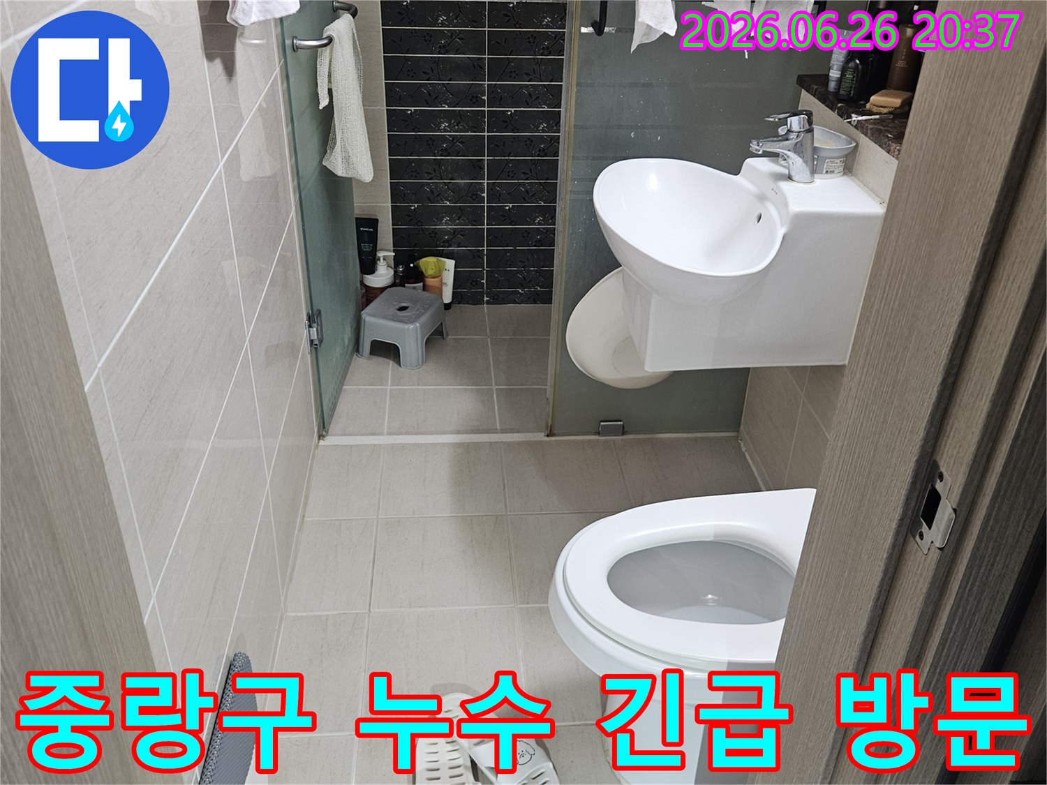 이 이미지는-서울 중랑구의 한 화장실에서-긴급하게 발생한 누수 문제를-해결하기 위해-현장 점검 중인 모습을 담고 있습니다-변기와 세면대가 보입니다