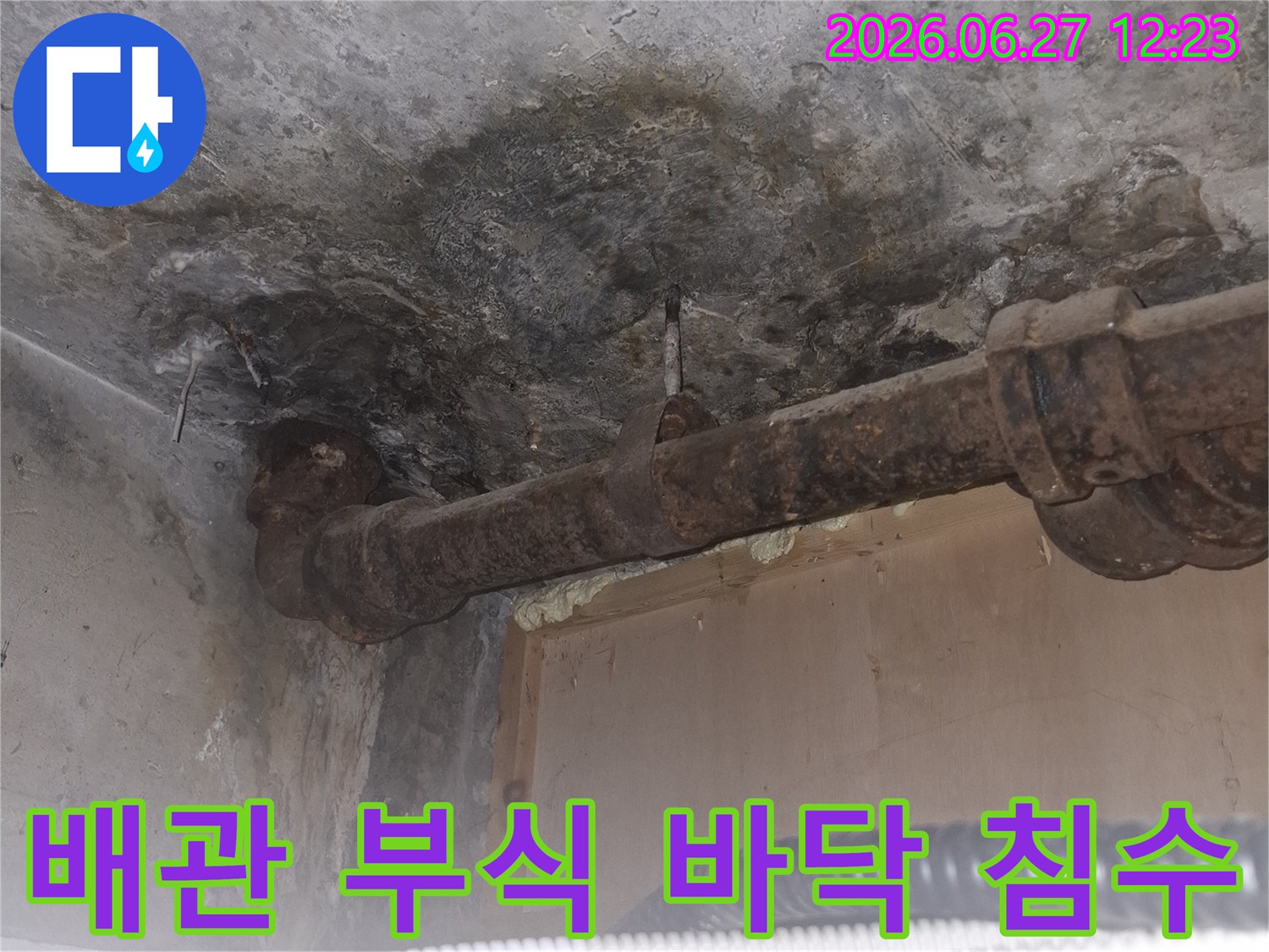 오래된 아파트의-녹슨 배관과-그 주변으로-물이 스며들어-어둡게 변색된-콘크리트 바닥의-누수 현장 사진입니다