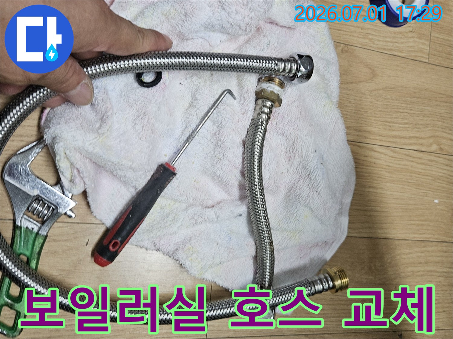 이 이미지는 주택 보일러실 급수관 연결 호스 교체를 위한-새로운 호스와 작업 도구를 보여주는 현장 사진입니다