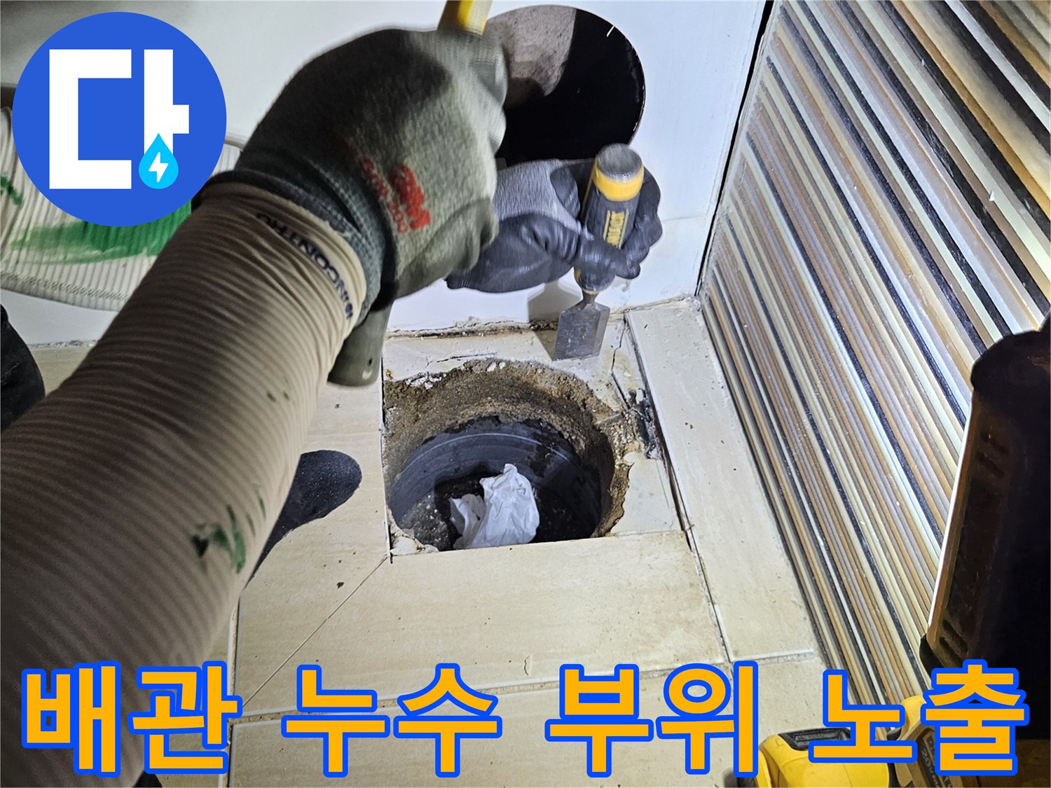 타공된 벽면 사이로 보이는 욕조 하수 배관과 작업용 드릴