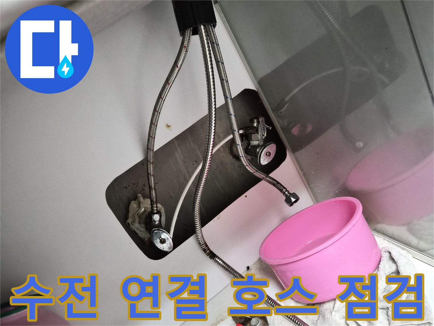 몽키스패너와 공구가 놓인 싱크대 하부장 내부의 수전 배관 모습입니다.