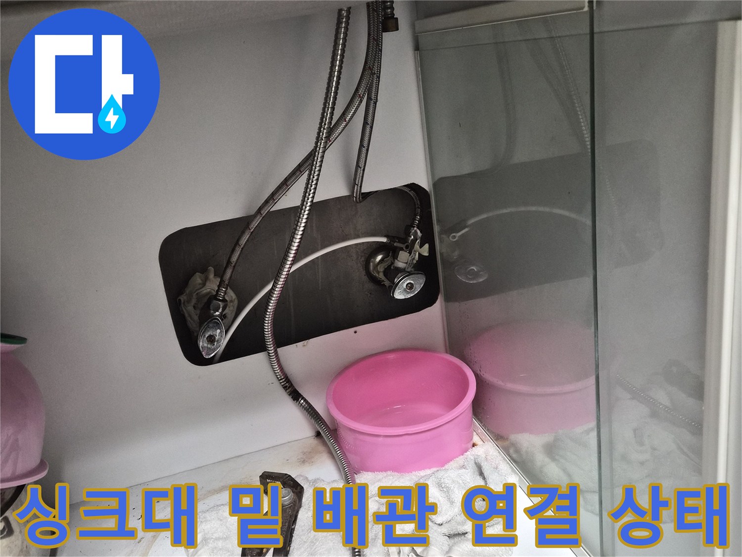 싱크대 하부장 내부의 수도 밸브와 유연한 호스 모습