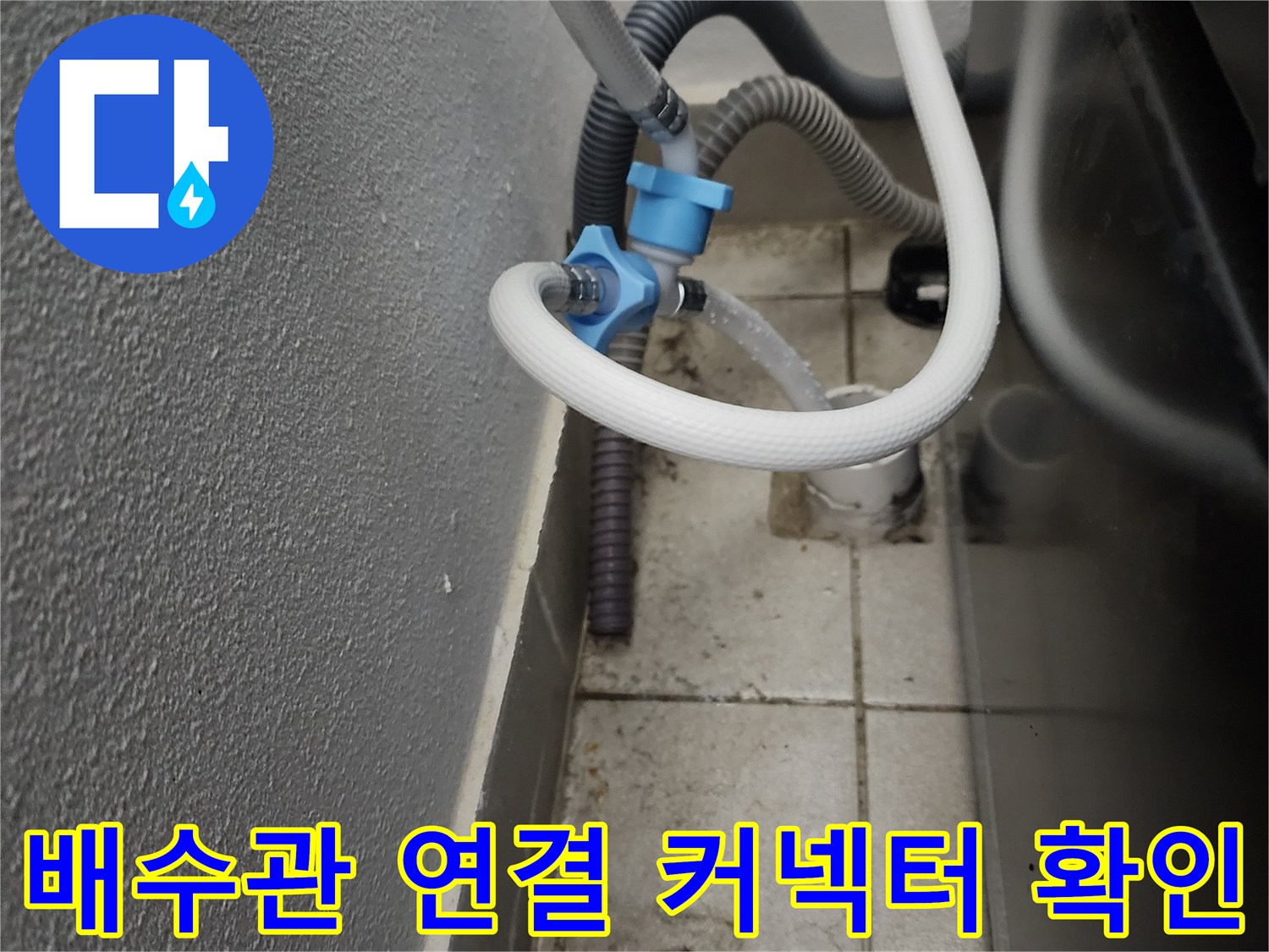파란색 커넥터로 체결된 배수 호스와 벽면 하수관의 근접 촬영
