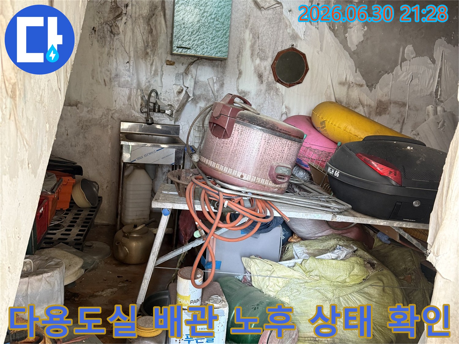 다용도실 내부에 적치된 물품들과 섞여 있는 노출 배관의 누수 여부를 점검하는 현장 사진