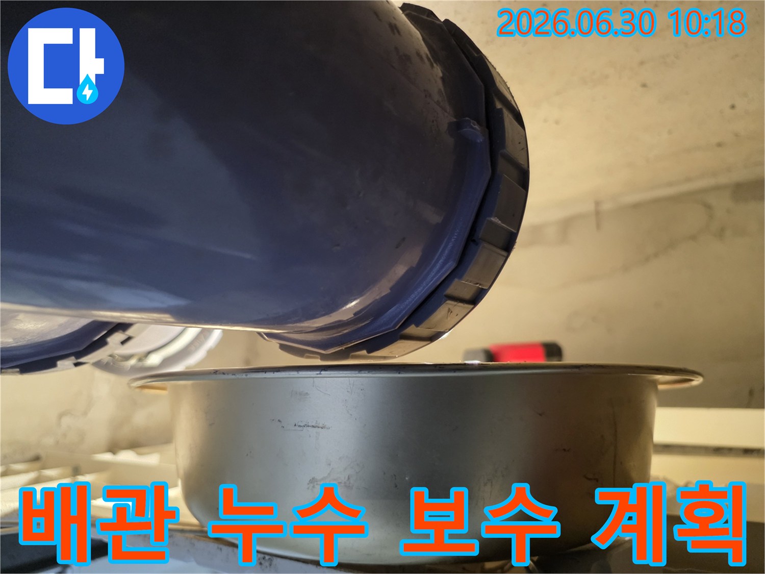 누수-현장에서-배관의-연결-부위에서-물이-새는-것을-발견하고-아래에-물받이를-놓아-누수-상황을-점검하고-보수-계획을-세우는-모습입니다.
