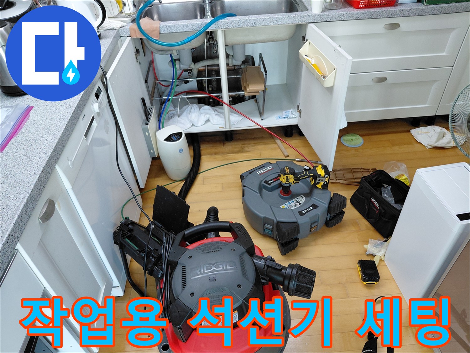 싱크대 밑 배관 작업을 위해 배치된 대형 석션기와 보조 도구