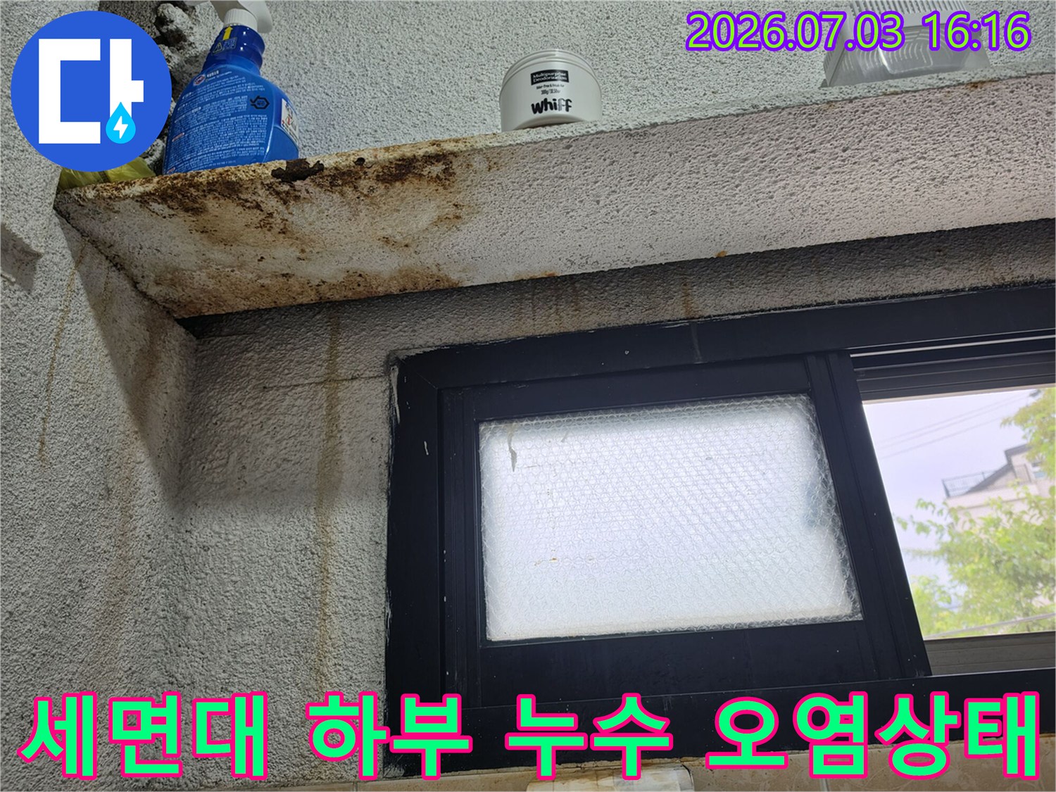 창문 프레임 옆으로 길게 내려온 누수 흔적과 세면대 아래쪽의 노출된 배관 부위