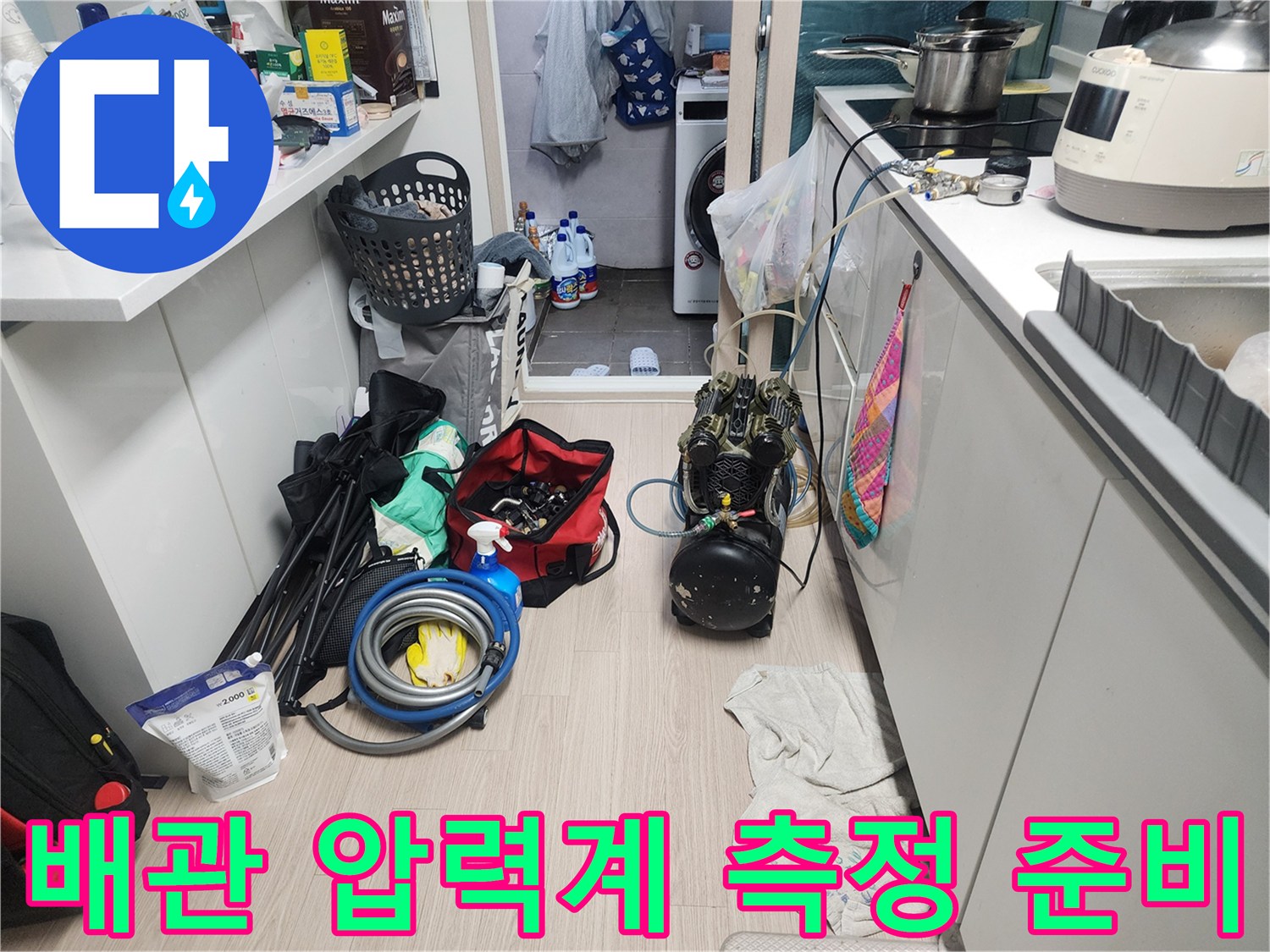 싱크대 하부 배관에 연결된 디지털 압력계와 각종 작업 도구들