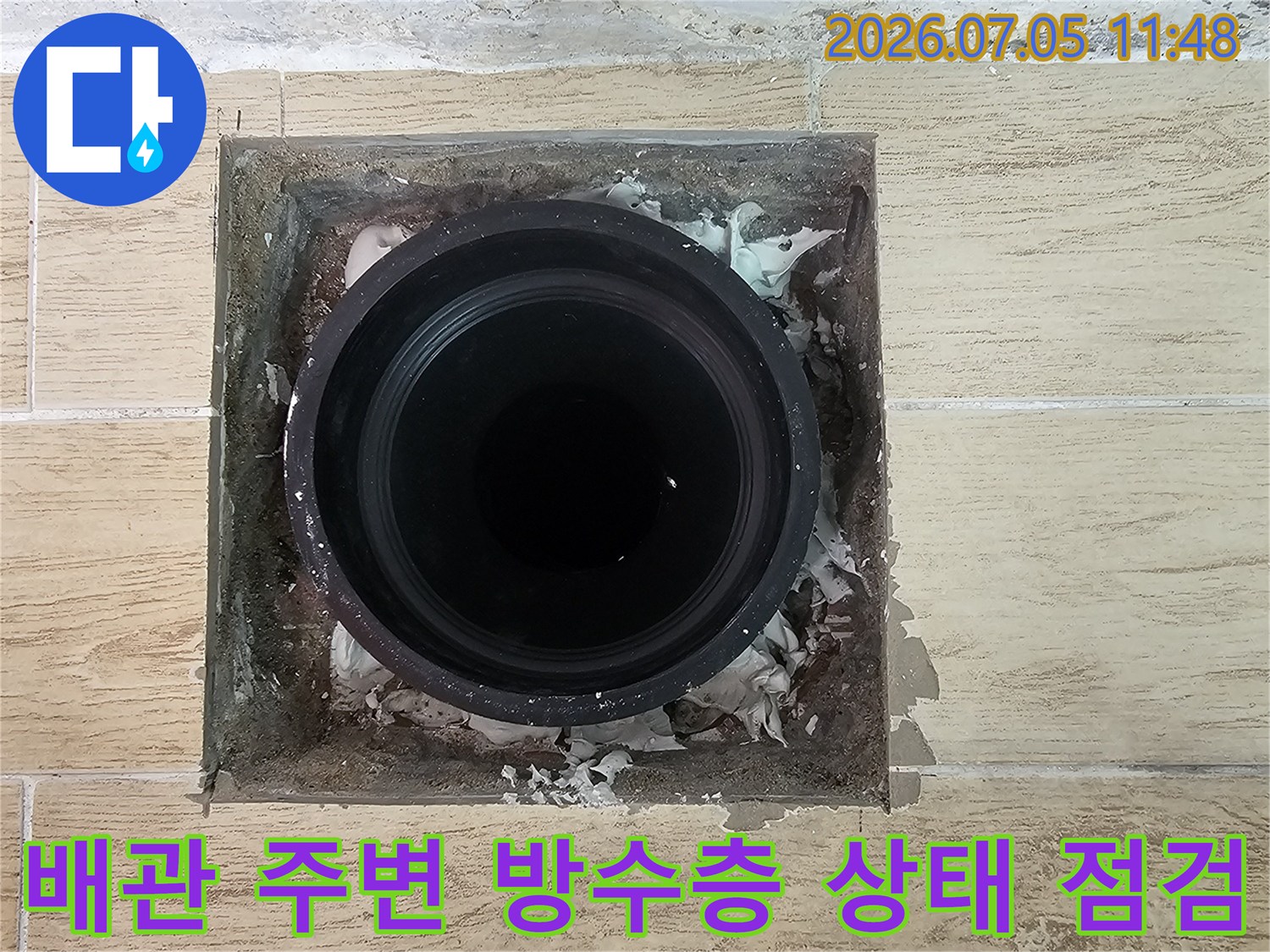 우수관과 드레인 배관이 만나는 지점의 노후된 마감재를 보여주는 클로즈업 사진.