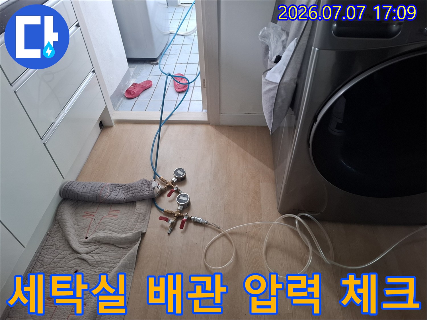 호스와 측정기를 활용해 세탁기 근처의 수분 누출 여부를 점검하는 장면