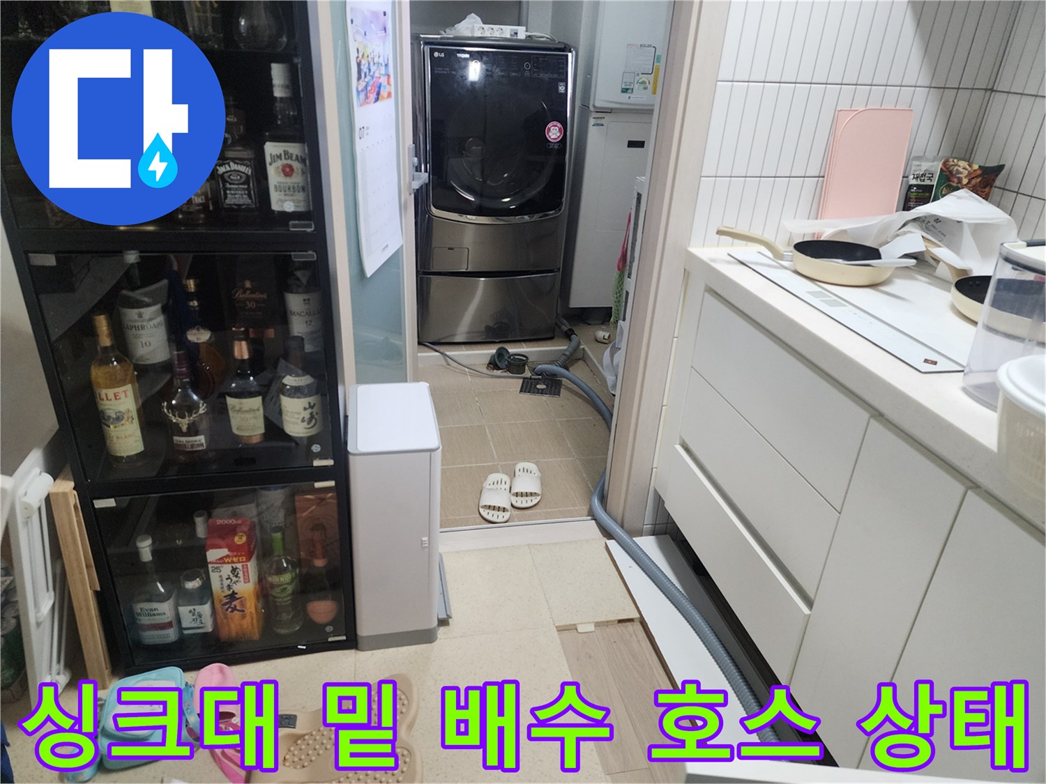 싱크대 하부장 아래 배수 관로와 주변 바닥재의 연결 부위를 촬영한 사진입니다.