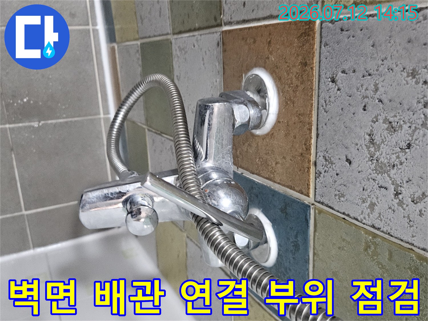 벽에 고정된 금속 수전 배관과 유연한 호스의 결합부 상세 촬영