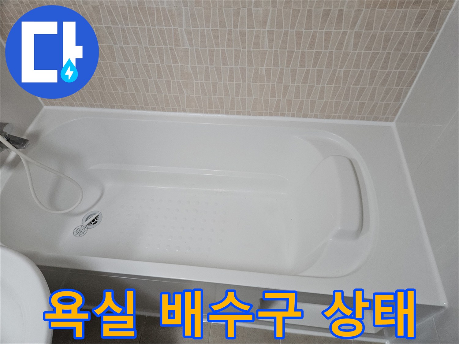 하얀색 욕조 내부의 배수구와 타일 벽면 모습
