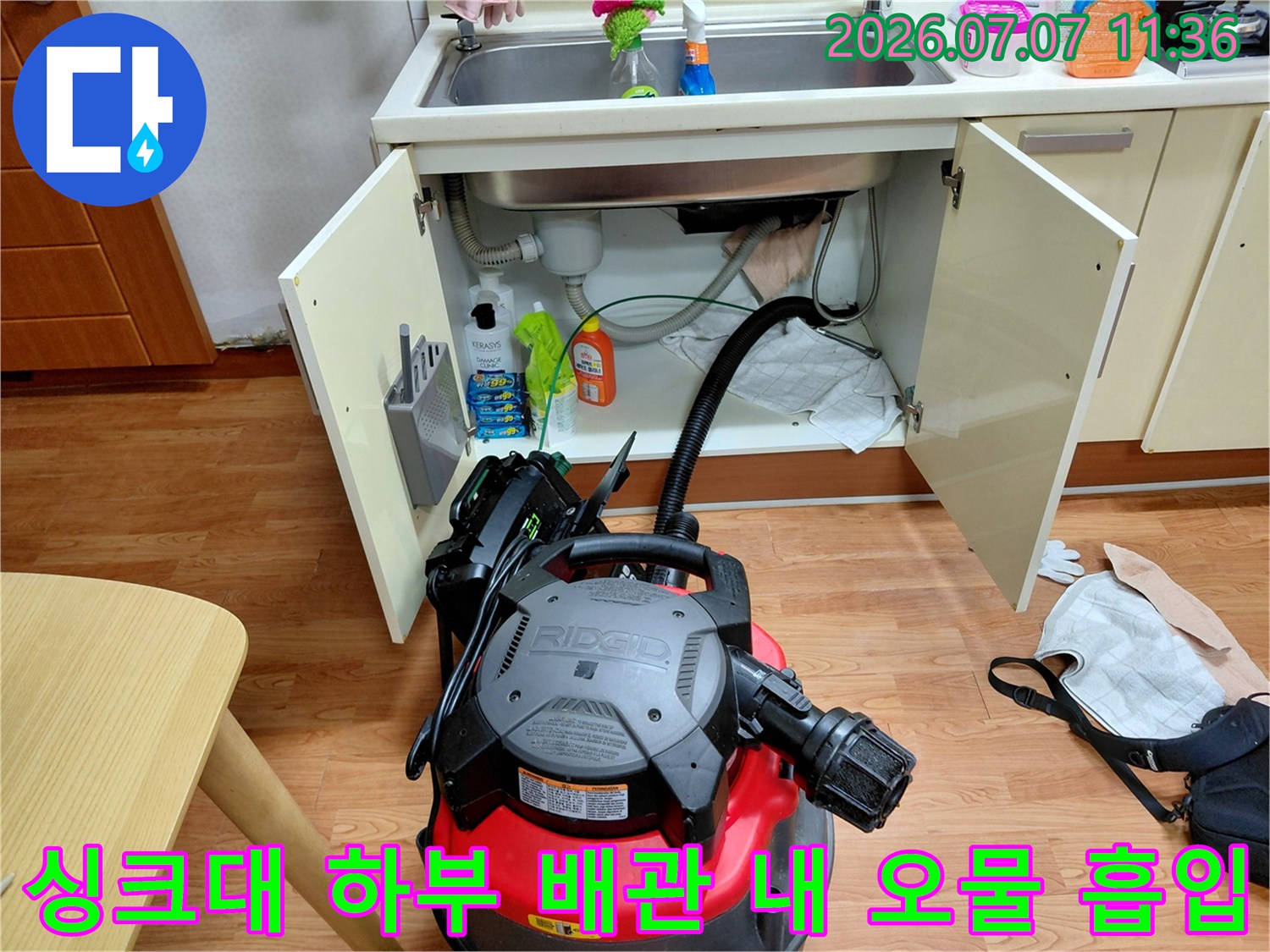 석션기를 활용하여 싱크대 아래쪽 배수구에 낀 이물질을 뽑아내는 공사 현장 모습