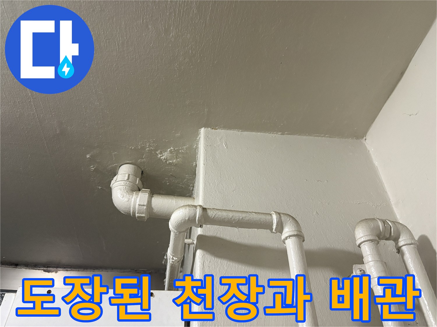 흰색으로 마감된 천장 구조물과 수직으로 내려오는 배수관 모습입니다.