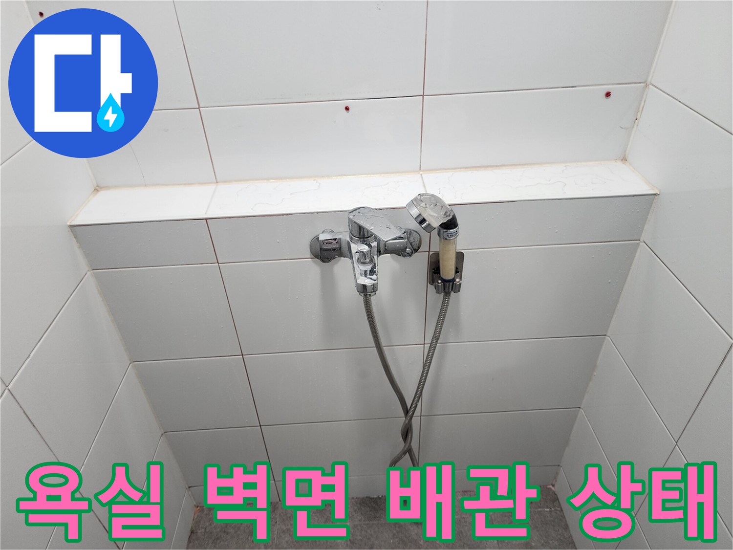 수도꼭지와 샤워 호스가 연결된 욕실 타일 벽면의 상세 모습