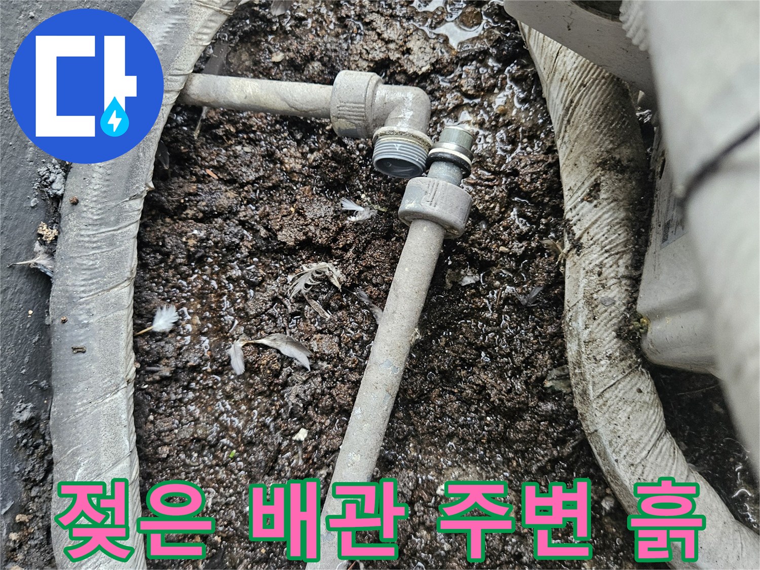 배관 연결 부위-주변의 젖은 흙과 이물질이 쌓여 있는 모습