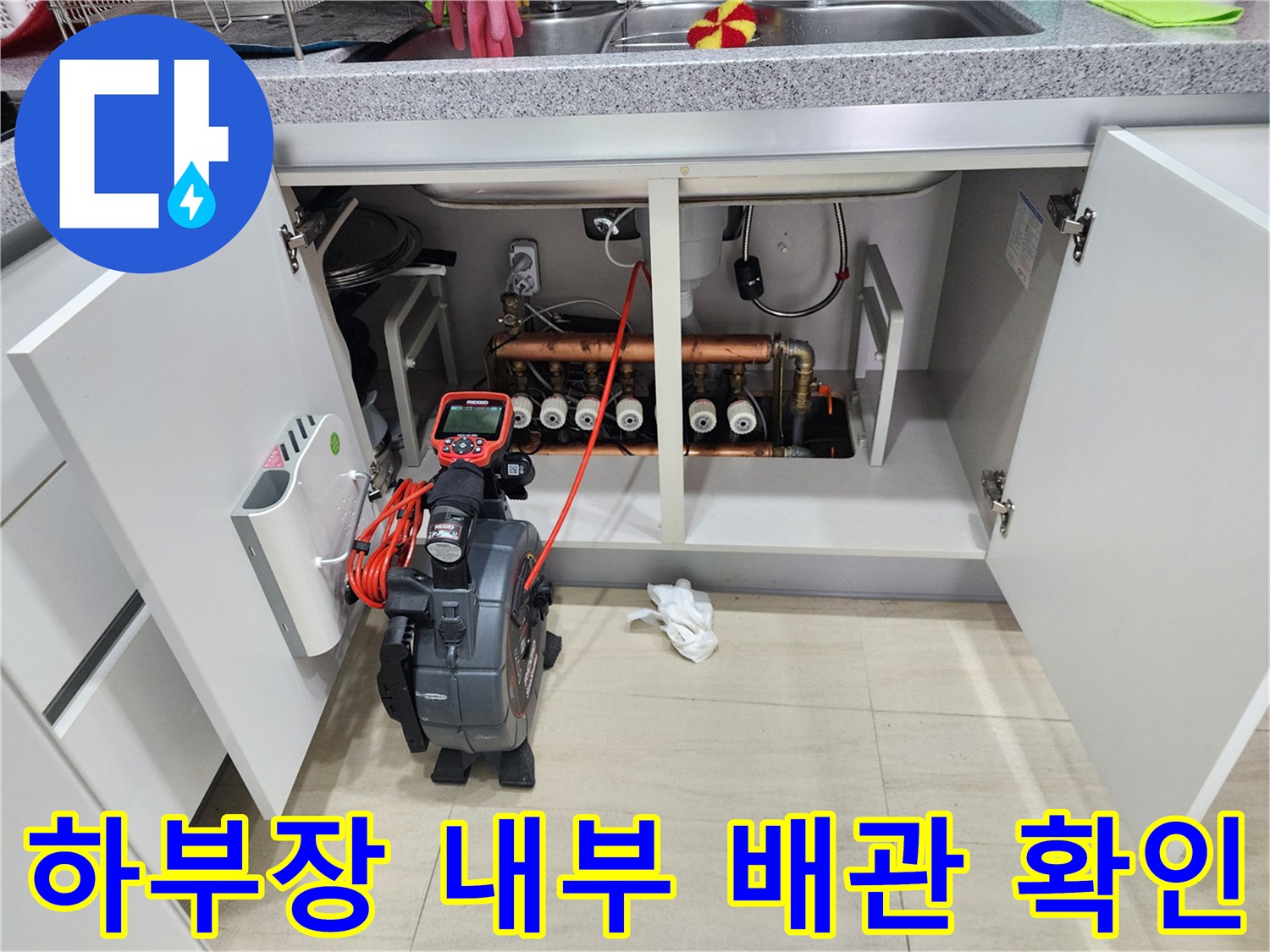 싱크대 아래 복잡한 배관 구조와 내시경 장비의 모습