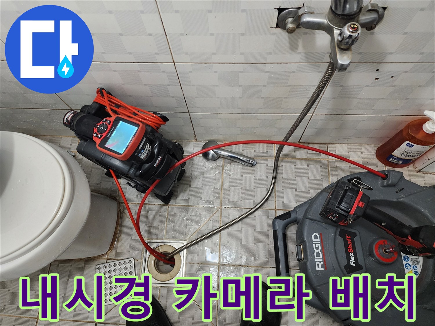 배수구 입구에 내시경 장비를 투입하여 배관 내부를 관찰하는 장면입니다.