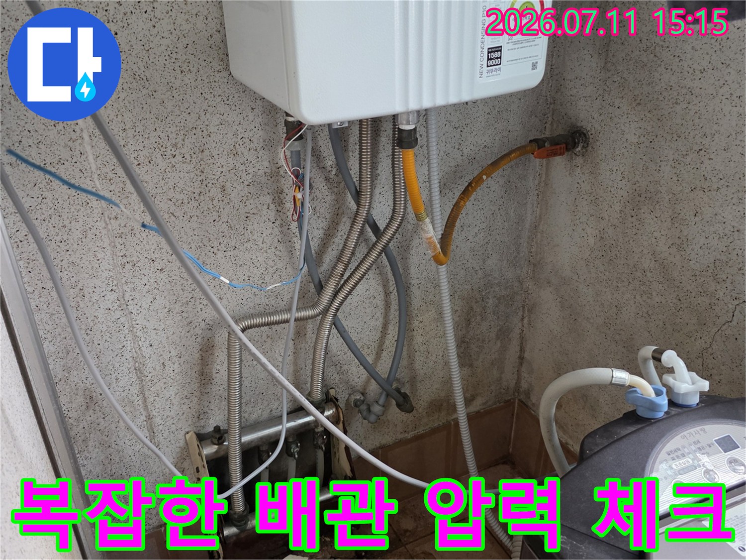 보일러 아래 복잡하게 얽힌 배관에 누수 탐지 장치를 연결한 모습