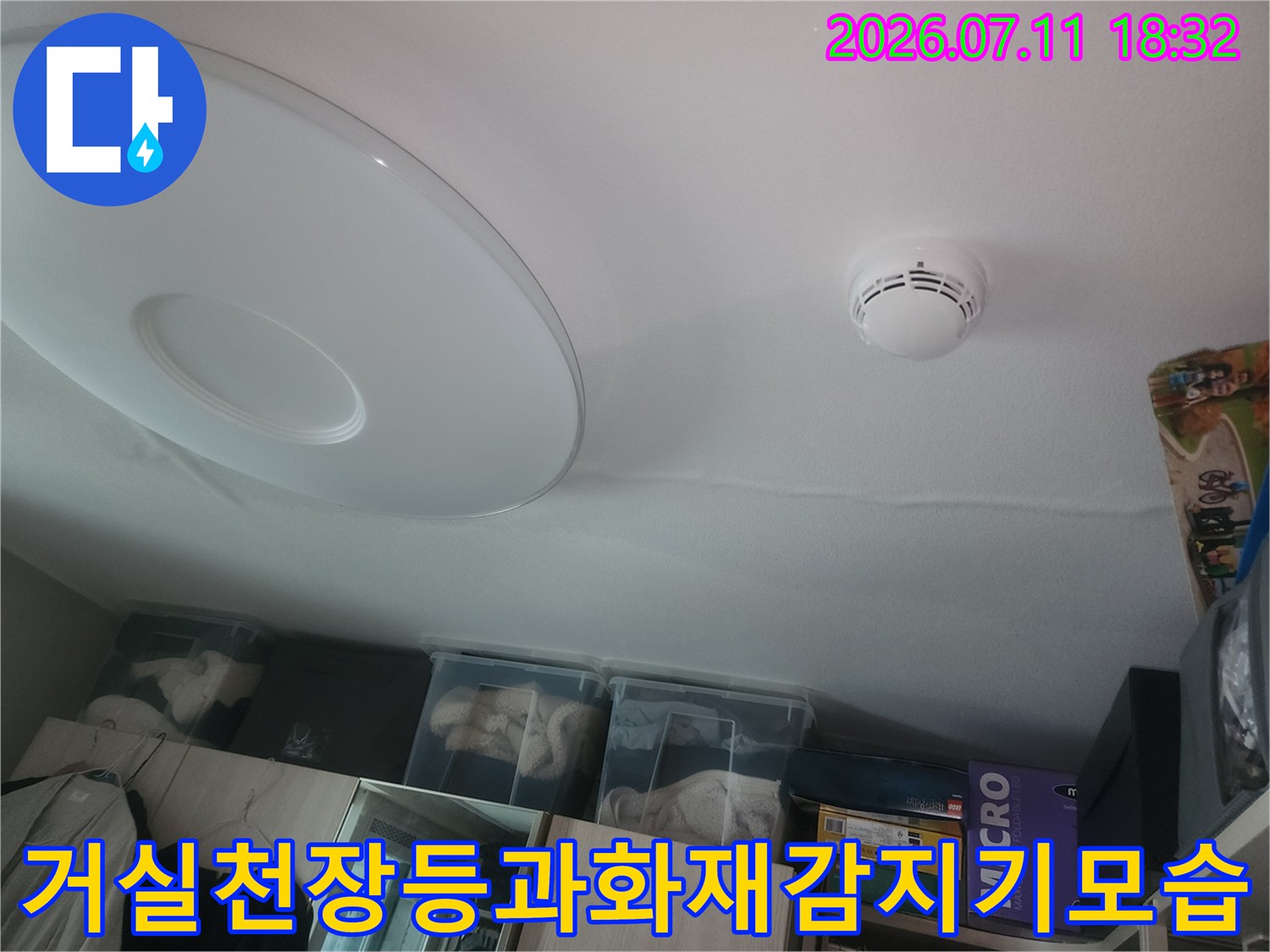 거실 천장 조명 기구와 화재 감지기가 설치된 실내 모습