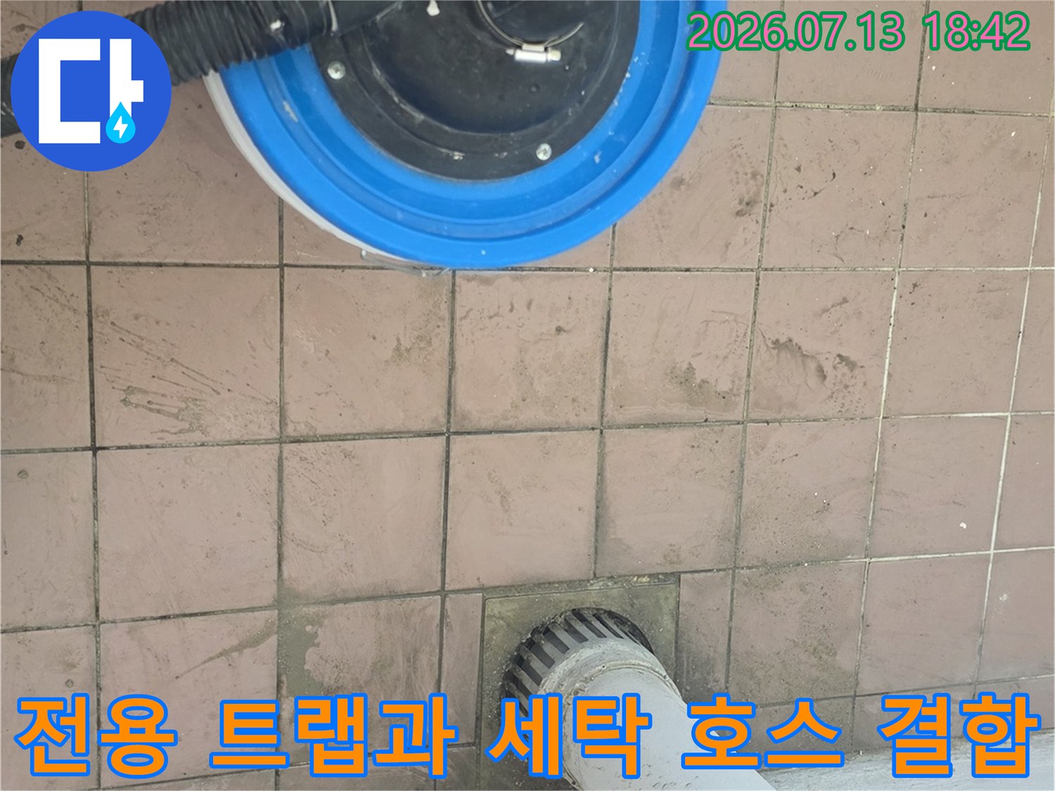 파란색 배수 트랩 위로 연결된 검은색 고무호스