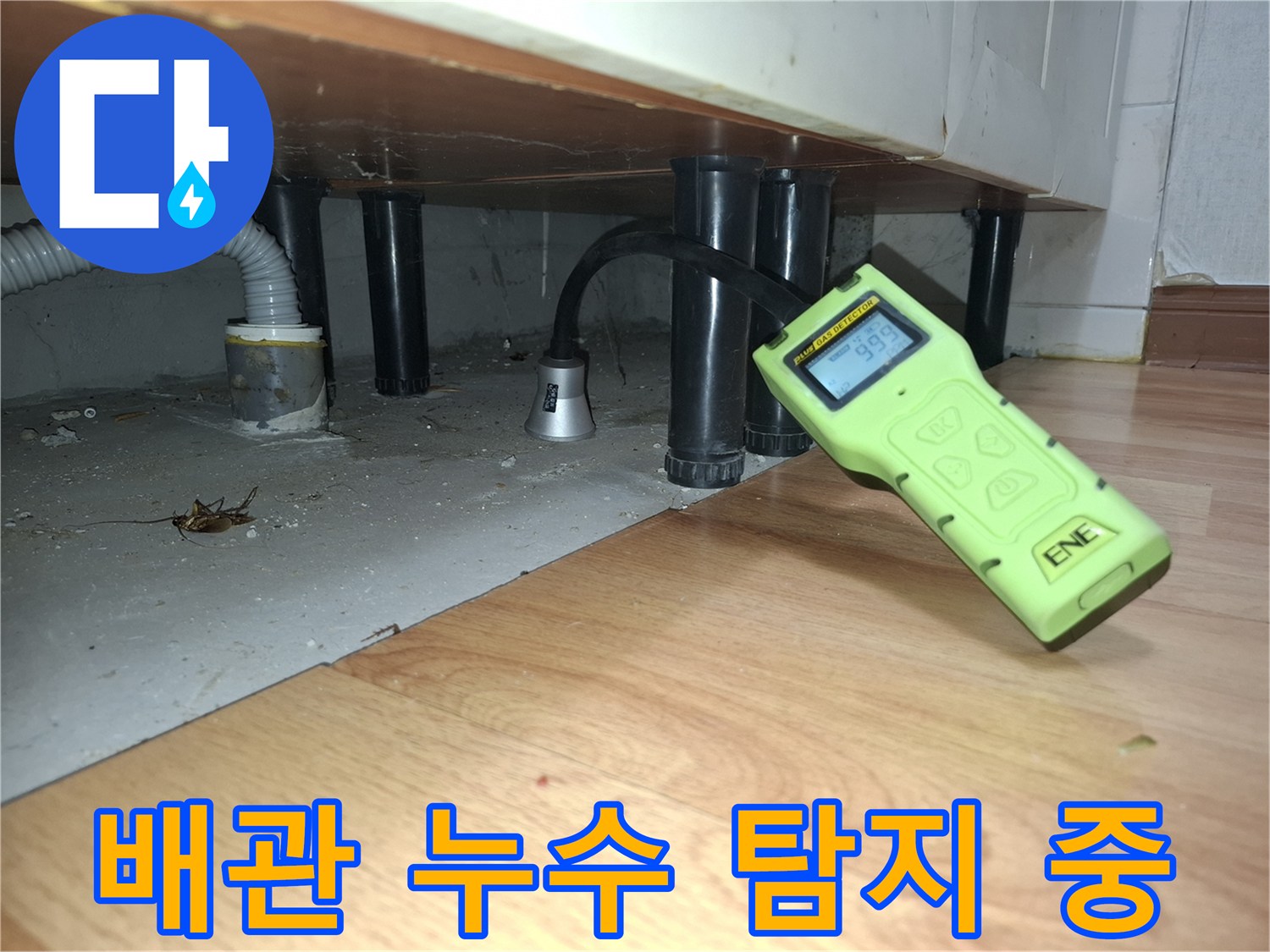 싱크대 아래 어두운 배관 사이로 가스 탐지 센서를 가까이 대고 있는 모습