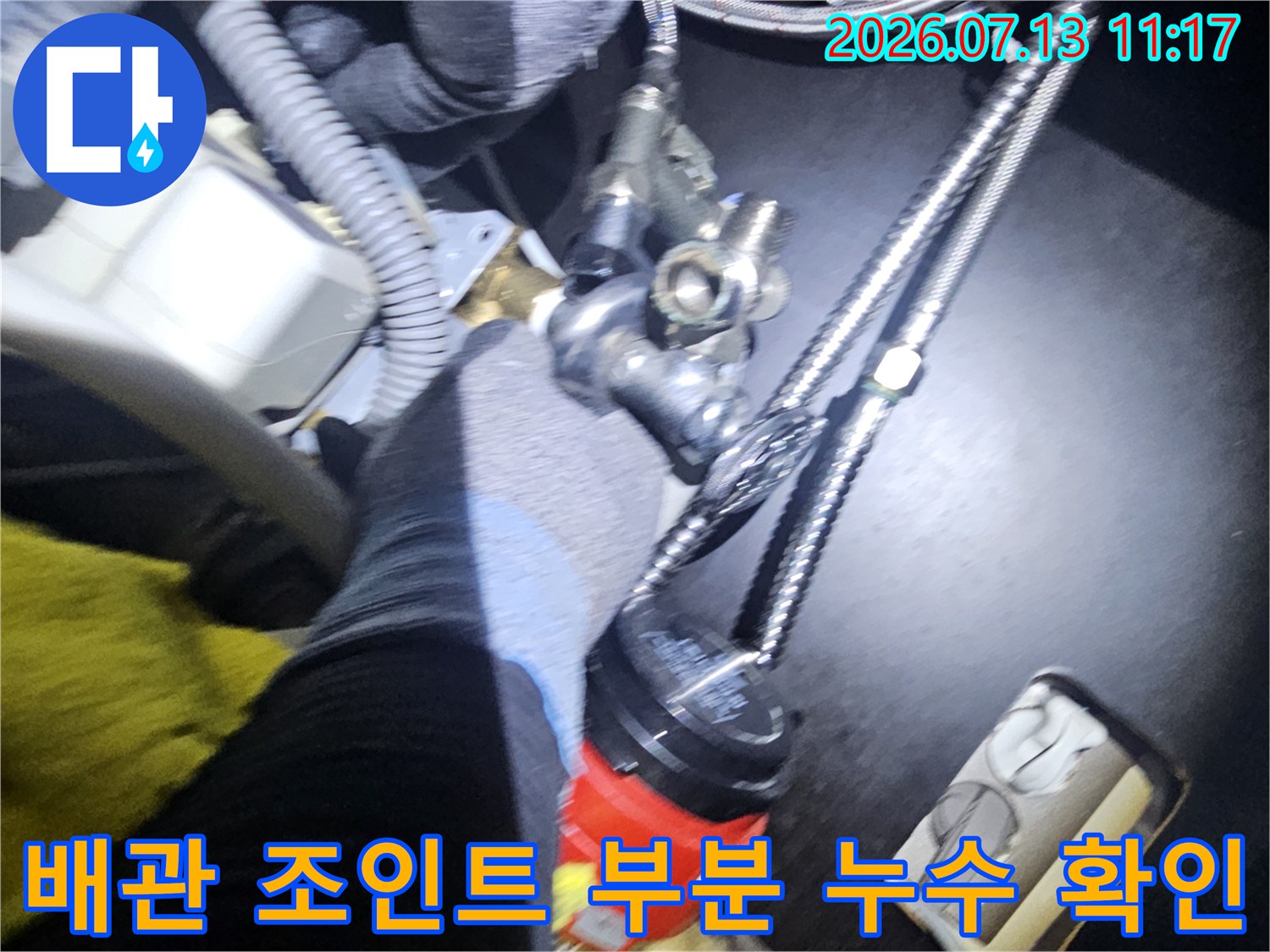 싱크대 하단 급수 밸브와 금속 배관이 연결된 부위를 점검 중인 엔지니어의 모습