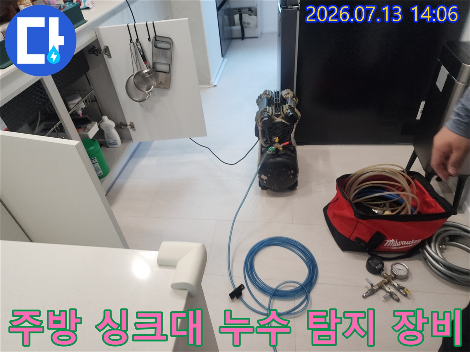 싱크대 하부장 앞에서 파란색 호스와 가압 장비를 연결해 누수를 점검하는 모습