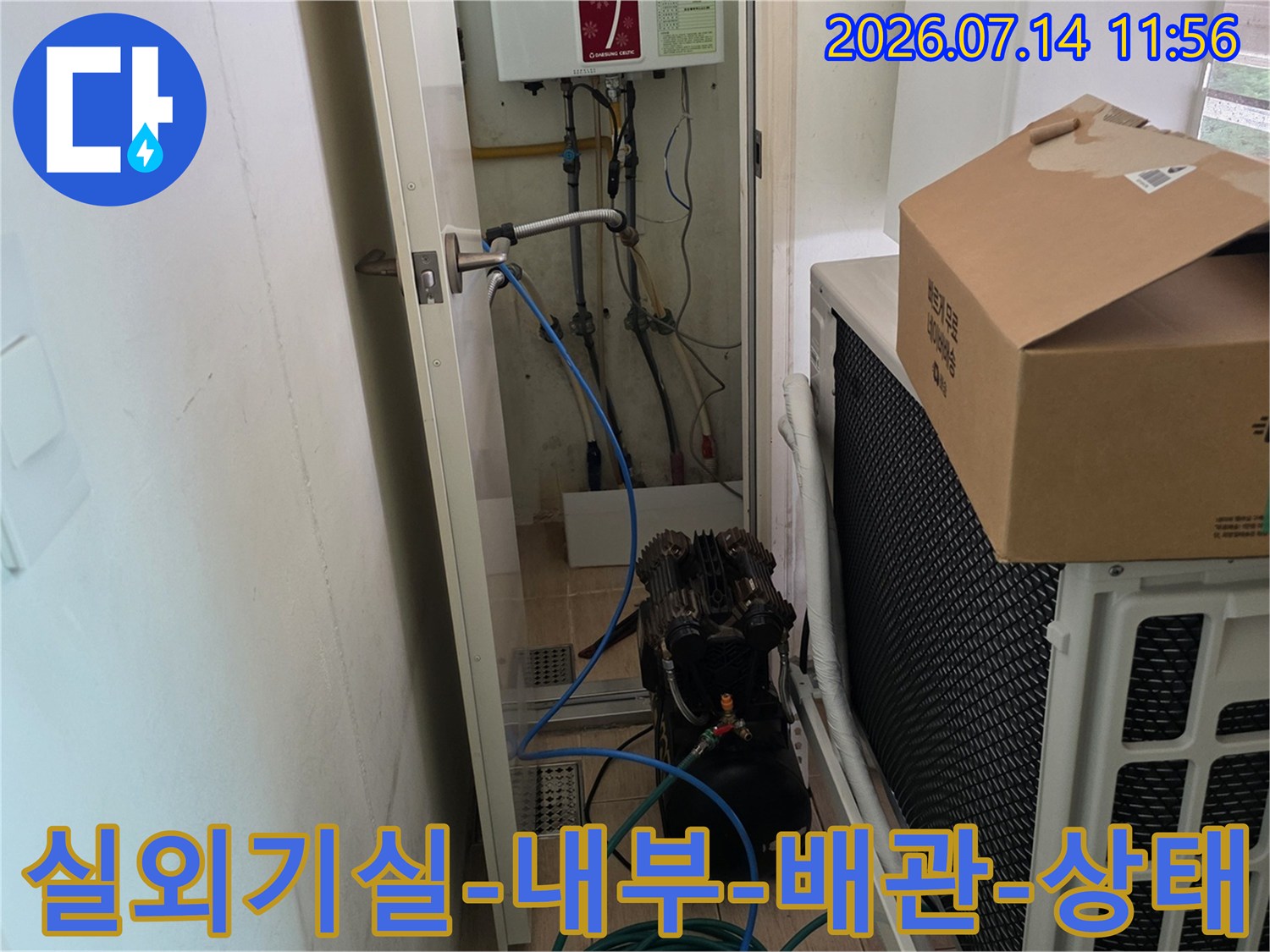 좁은-공간에-위치한-실외기와-그-옆의-분전함-및-파란색-배관들