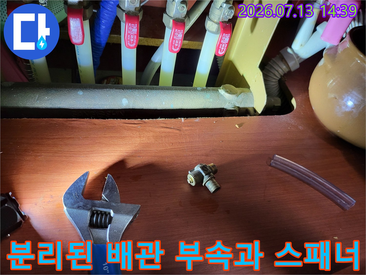 누수가 발생한 분배기 연결 부품-작업 도구인 몽키스패너가 나란히 배치된 모습