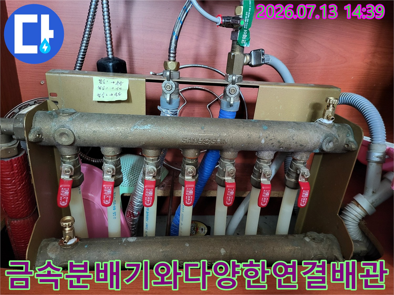 상단에 파란색 배관과 은색 호스가 연결된 금속제 난방 분배기 시스템