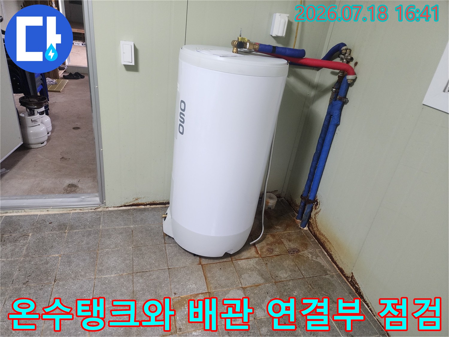 흰색 온수 탱크 옆에 설치된 파란색과 빨간색의 배관 시설물