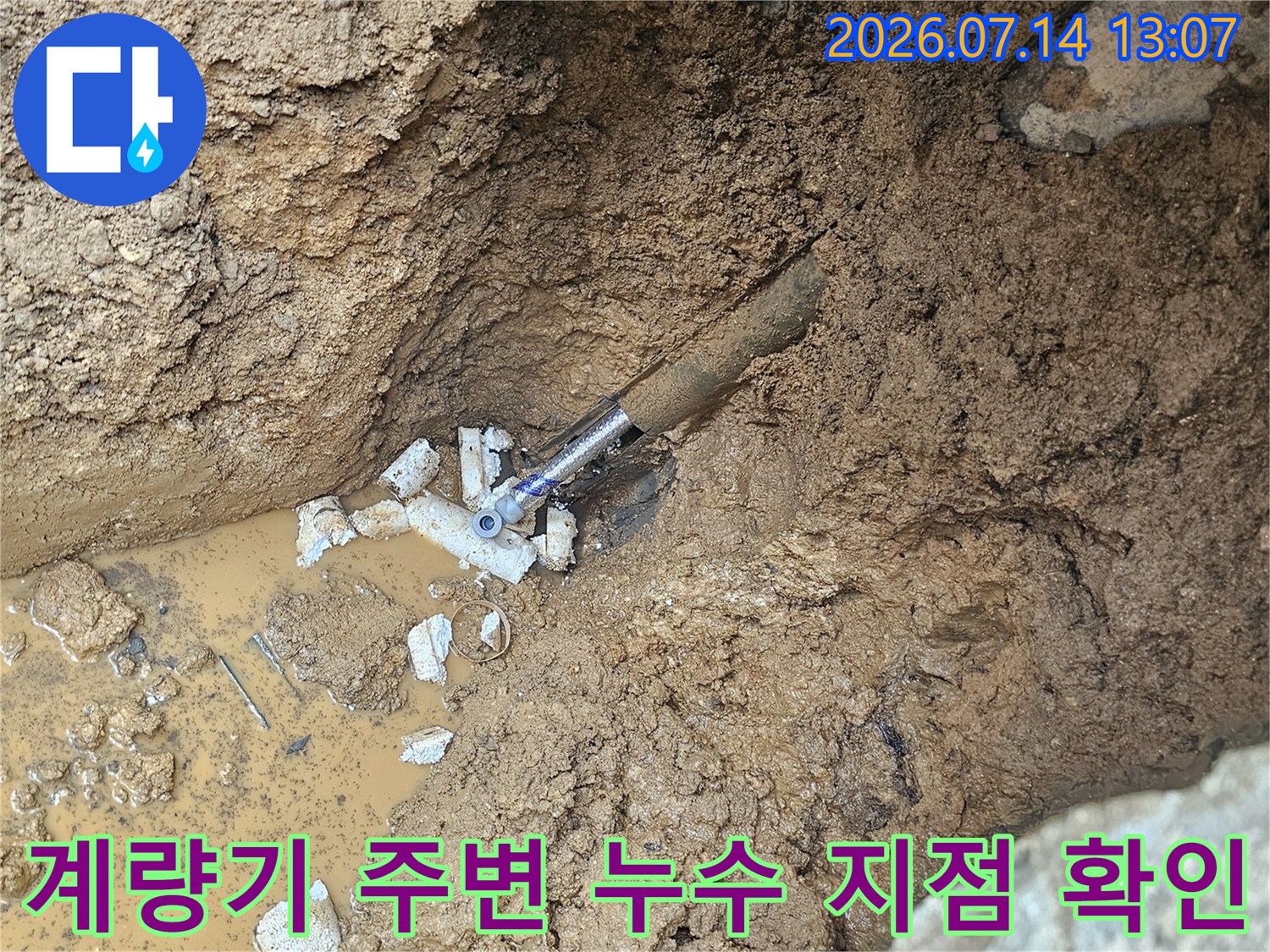 흙으로 덮인 계량기 앞 배관 연결 부위에서 물이 새어 나오는 현장 모습