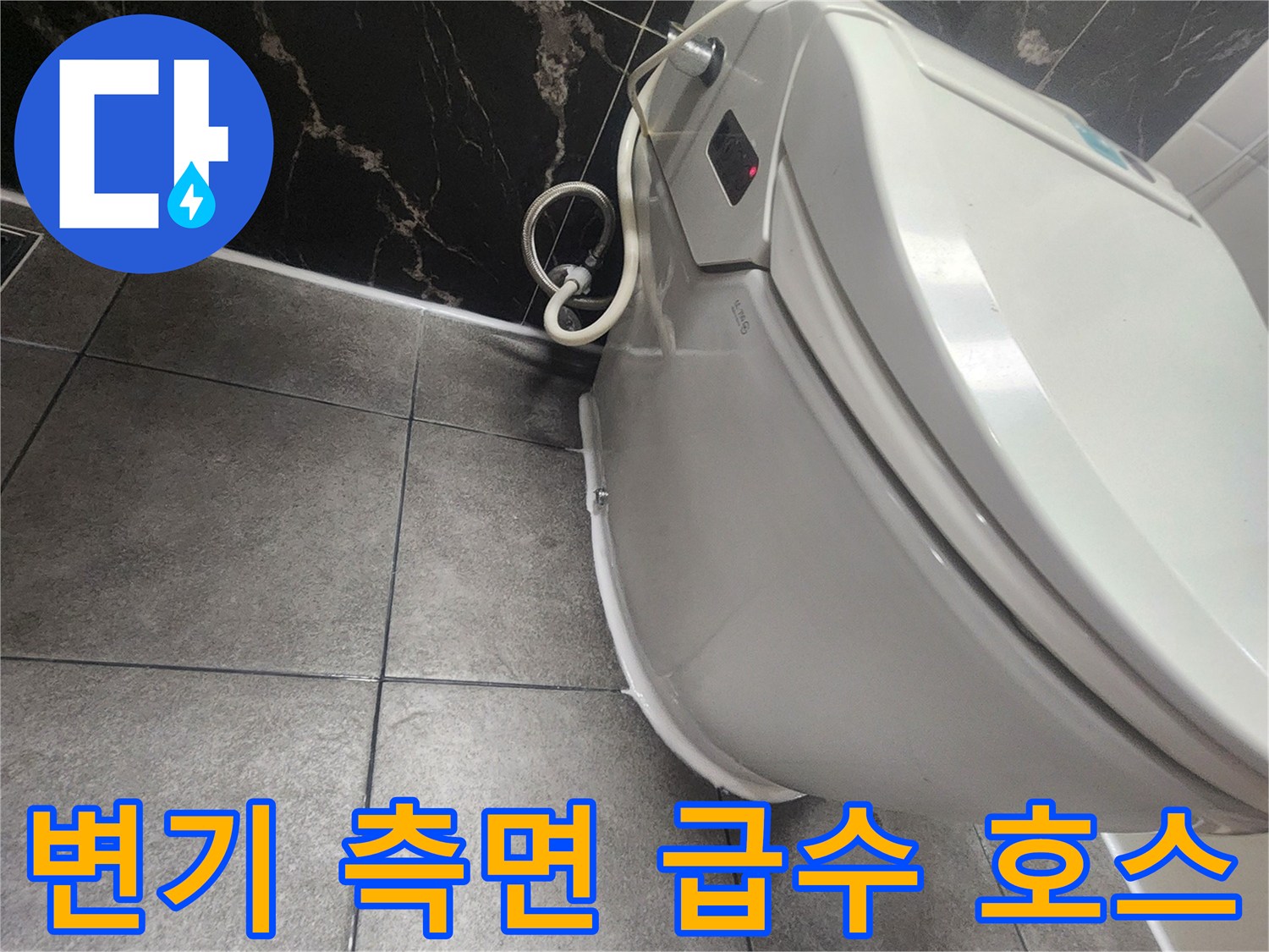 변기 옆쪽의 굴곡진 급수관과 바닥 타일 모습