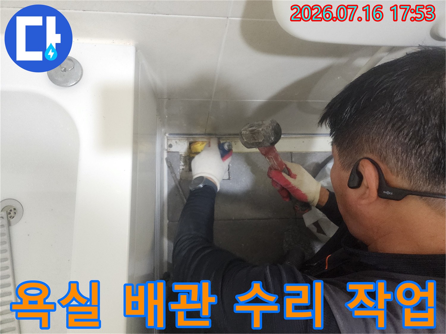 작업자가 장갑을 끼고 욕실 바닥 아래 노출된 배관 부위를 공구로 정밀하게 조절하는 모습