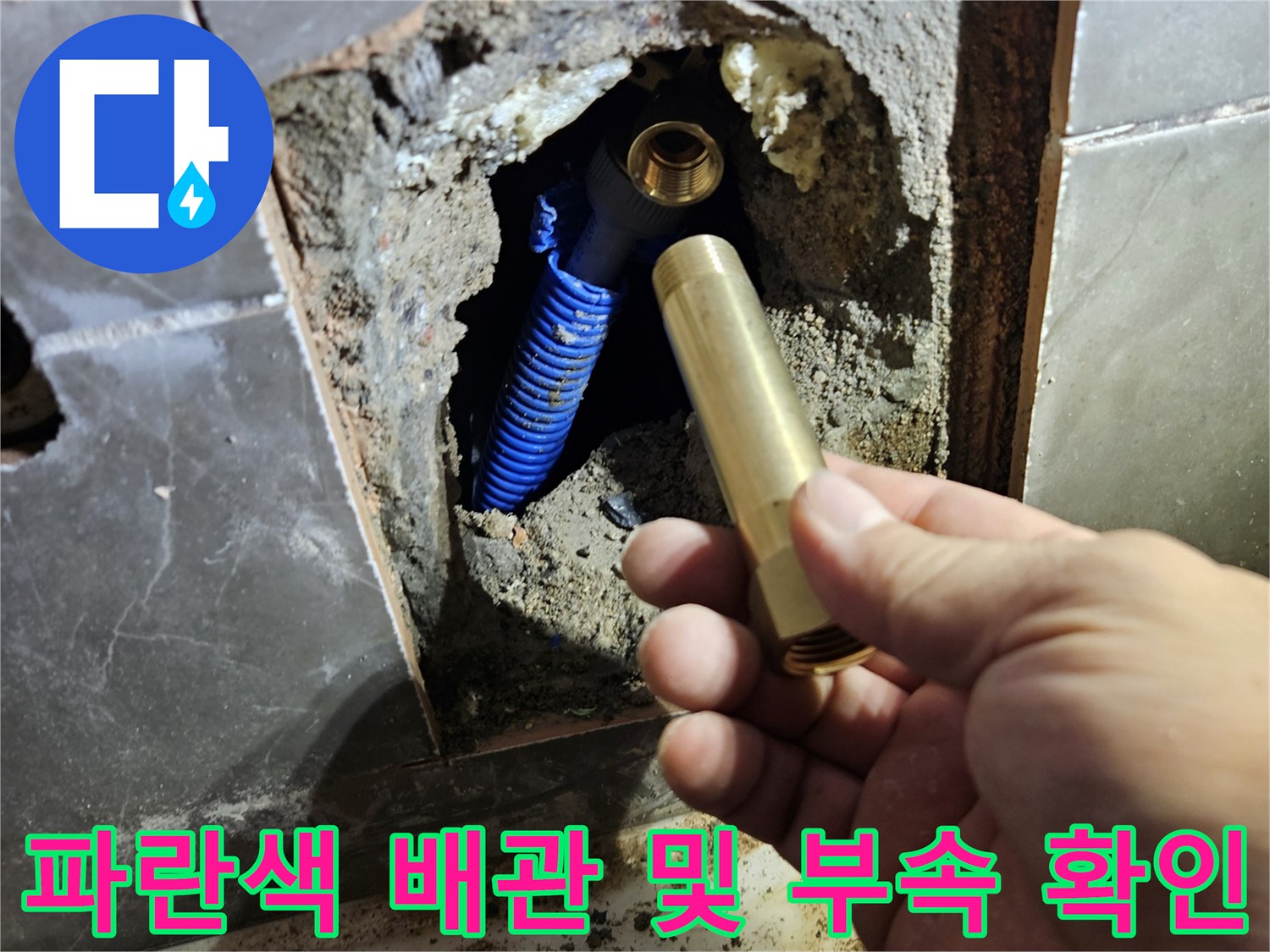 벽면 내부의 파란색 배관과 황동색 연결 부품 노출 상태