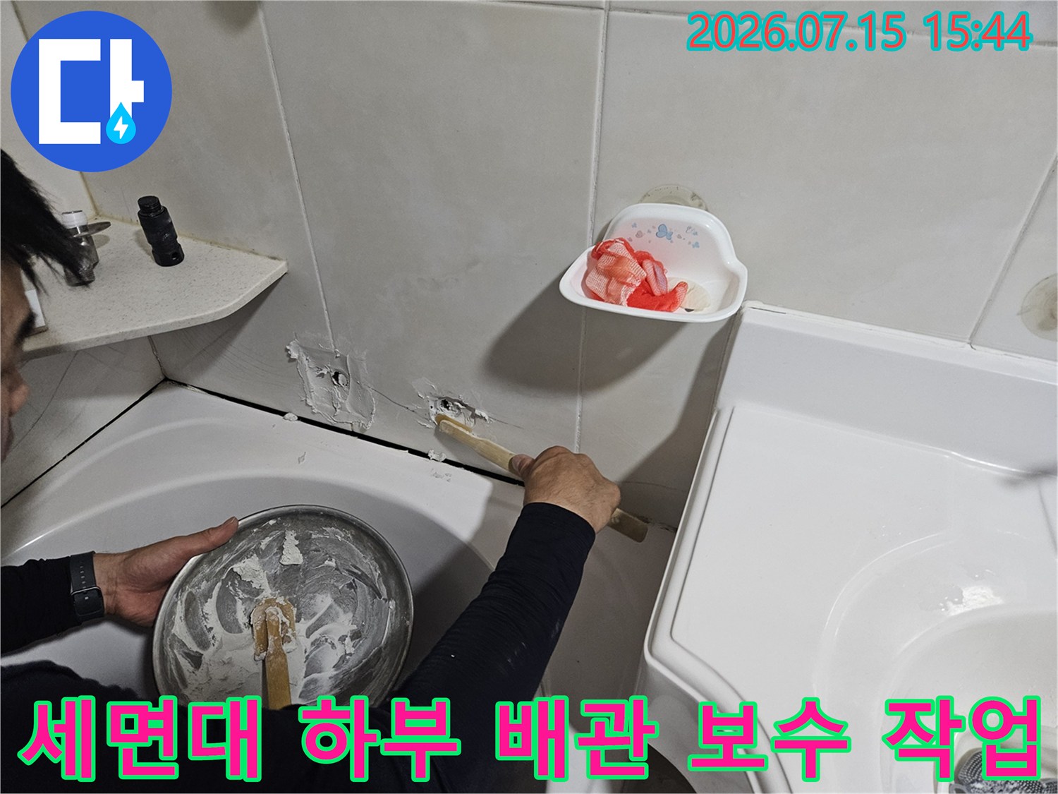 기술자가 세면대 아래쪽 파손된 배관 부위를 수리하는 모습